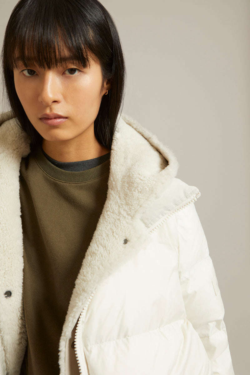 A line down jacket in a mix of technical fabrics with merino shearling hooded bib