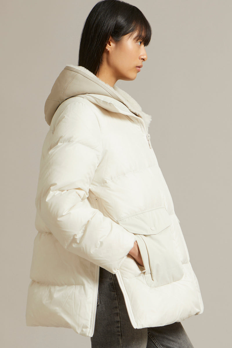 A line down jacket in a mix of technical fabrics with merino shearling hooded bib